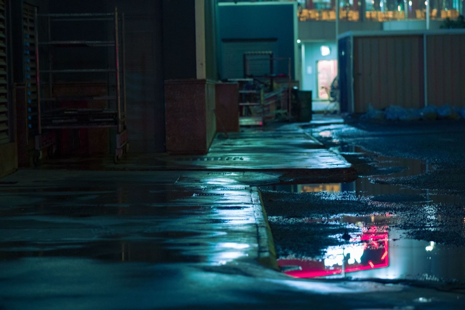 Rain-soaked alley glowing with reflected blue and pink practical lights