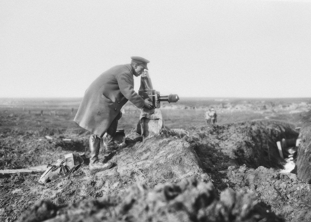 Black-and-white image of a soldier photographing a battlefield trench